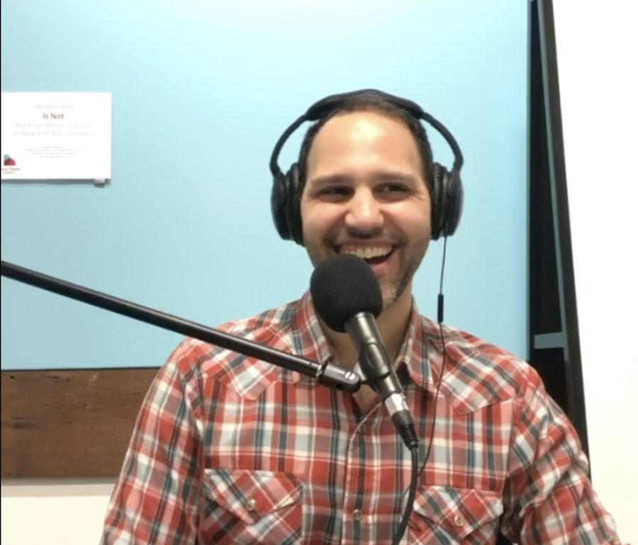 Amer laughing in headphones behind a microphone in the podcast studio